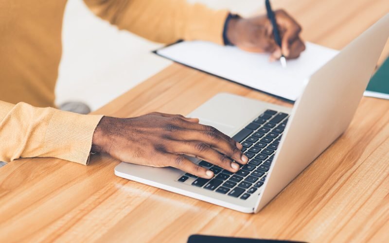 unrecognizable-black-guy-working-on-his-laptop